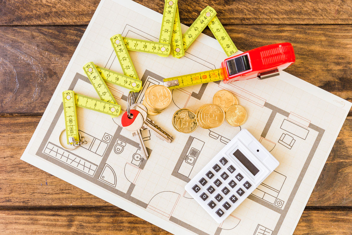 elevated-view-measure-tape-stacked-coins-key-calculator-blueprint-construction-budget-management