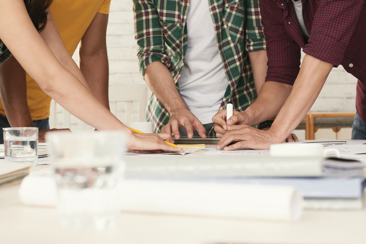 unrecognizable-casually-dressed-people-standing-around-table-brainstorming-risk-management-strategies