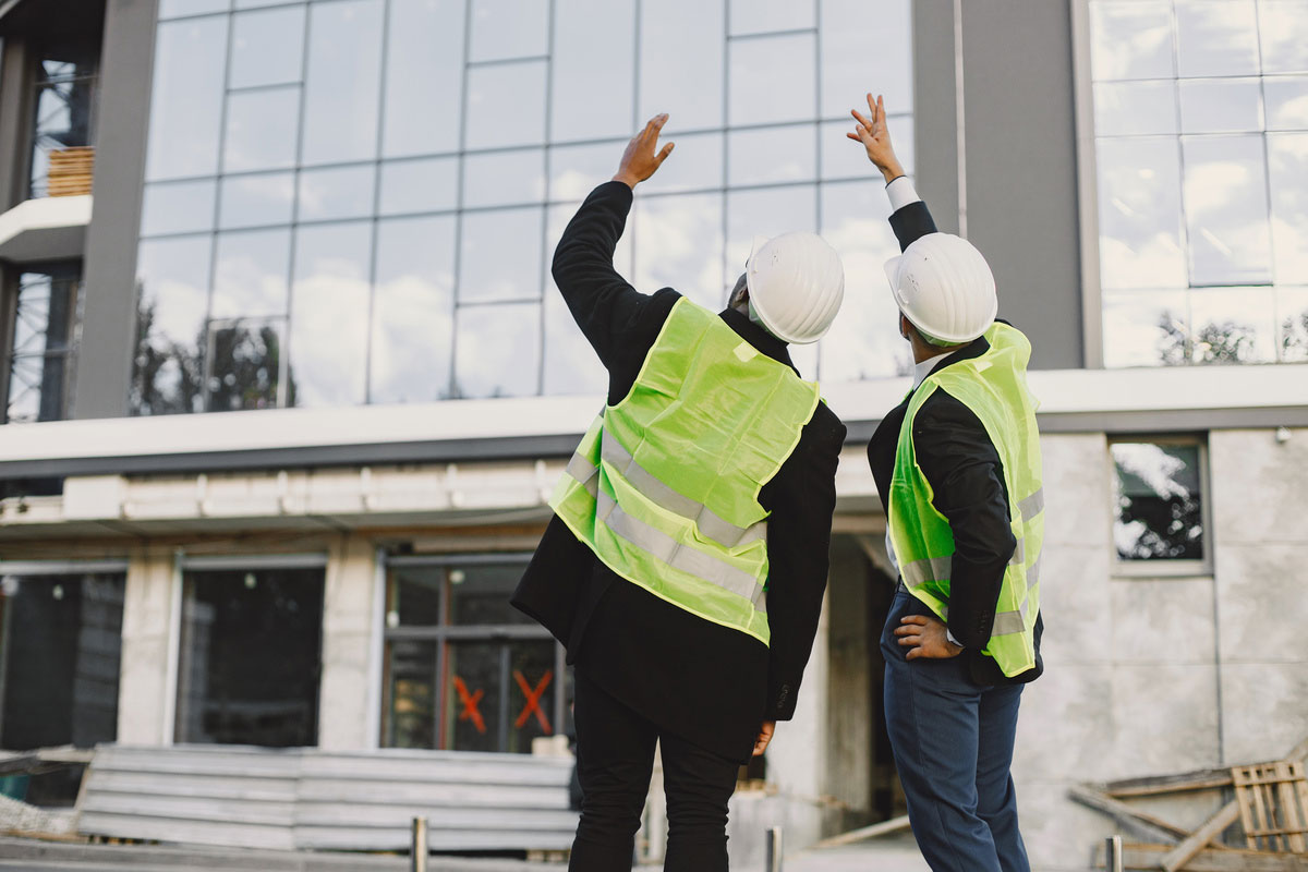 multi-racial-builders-standing-outdoors-back-view-wearing-uniform-talking-about-Construction-Statistics