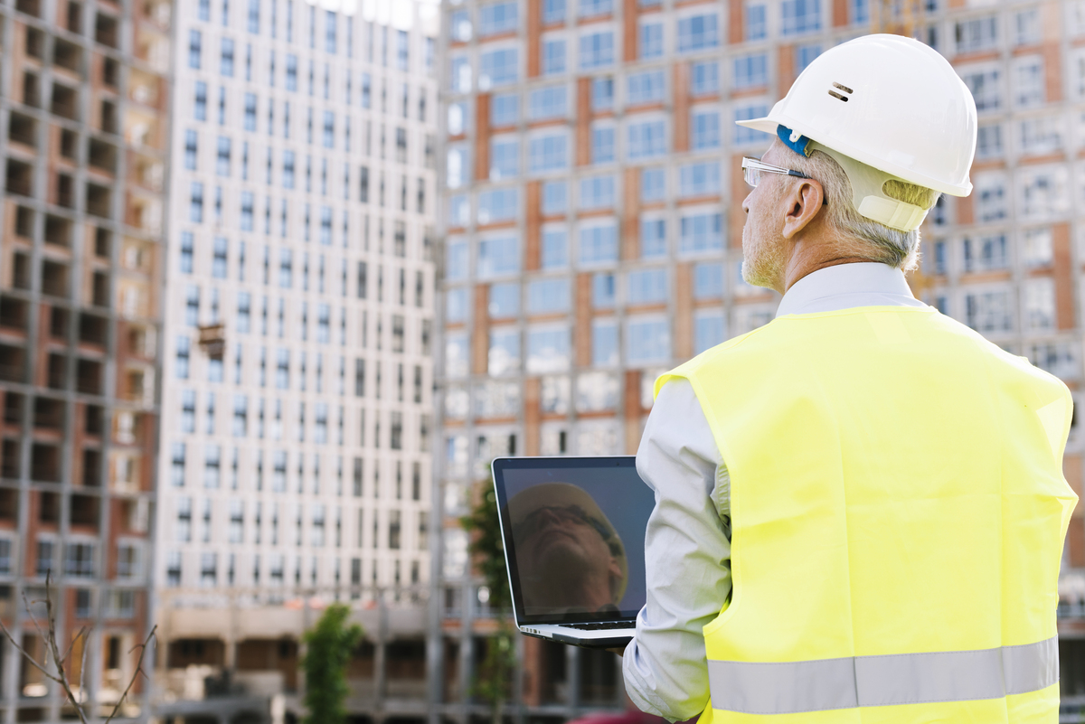 back-view-old-man-with-helmet-holding-laptop-digital-twin-software