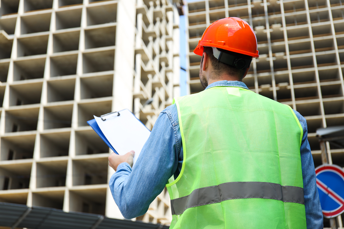 Civil-Engineer-in-Safety-Hat-With-Clipboard-Against-Construction-Submittal-in-Construction