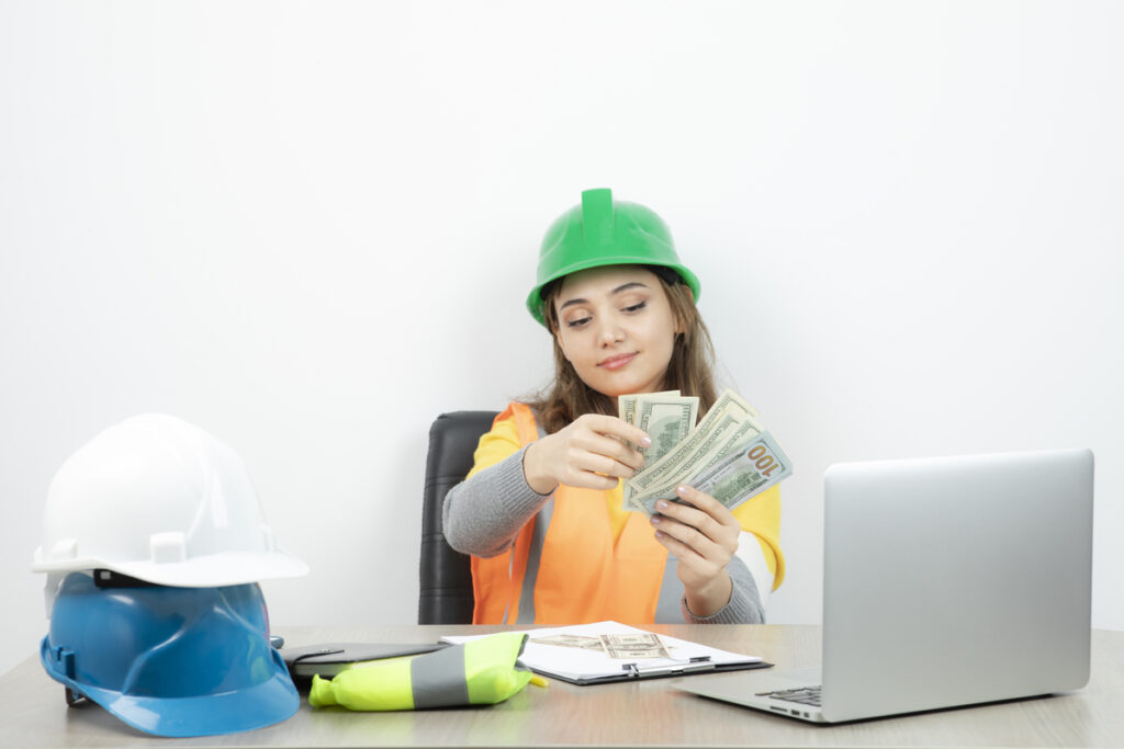 worker-female-orange-vest-green-helmet-sitting-desk-high-quality-photo-Cash-Flow-in-Construction