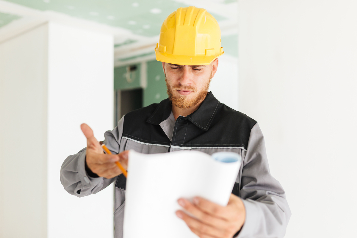 young-serious-engineer-work-clothes-yellow-hardhat-thoughtfully-looking-plan-new-apartment-work-Prevent-Construction-Project-Delays