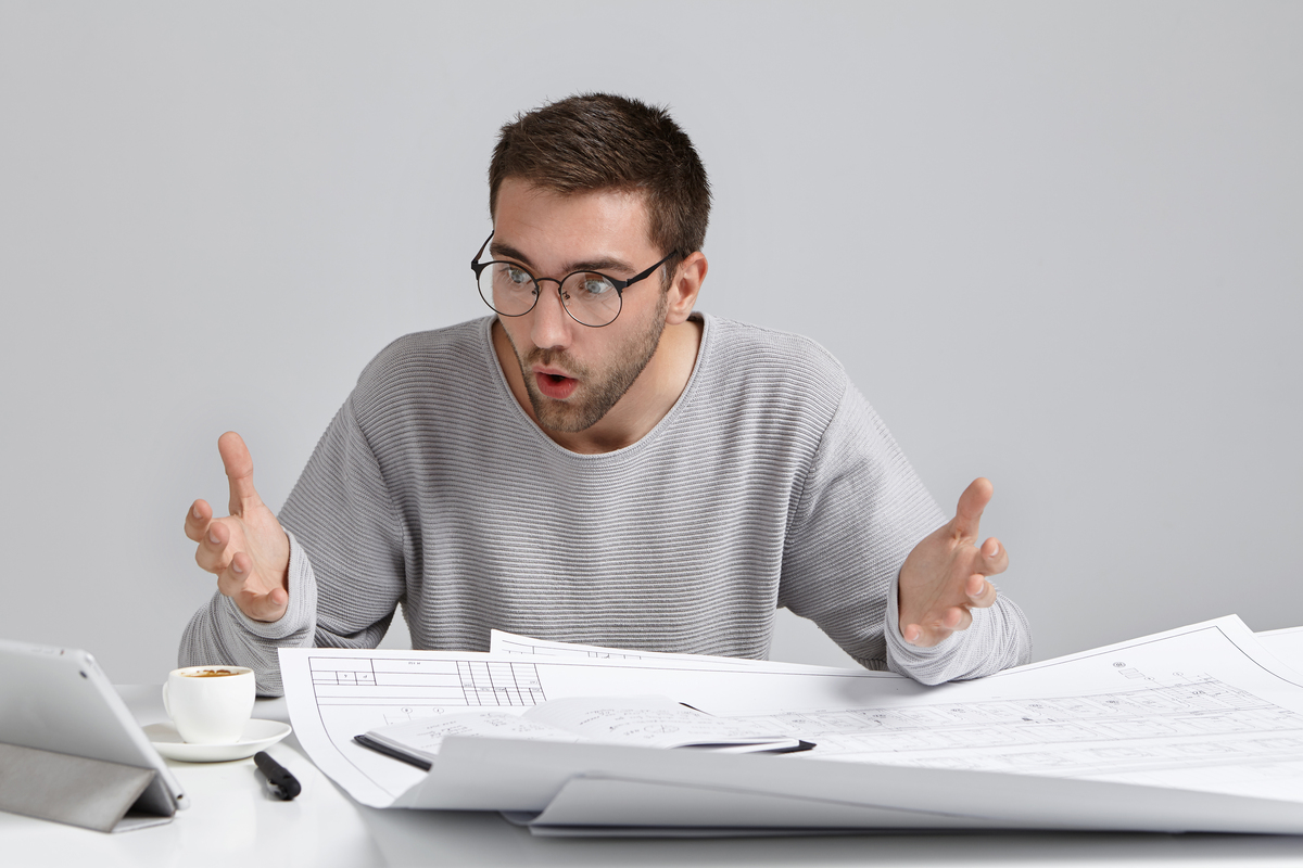 horizontal-portrait-puzzled-male-designer-stares-screen-laptop-Construction-Project-Delays