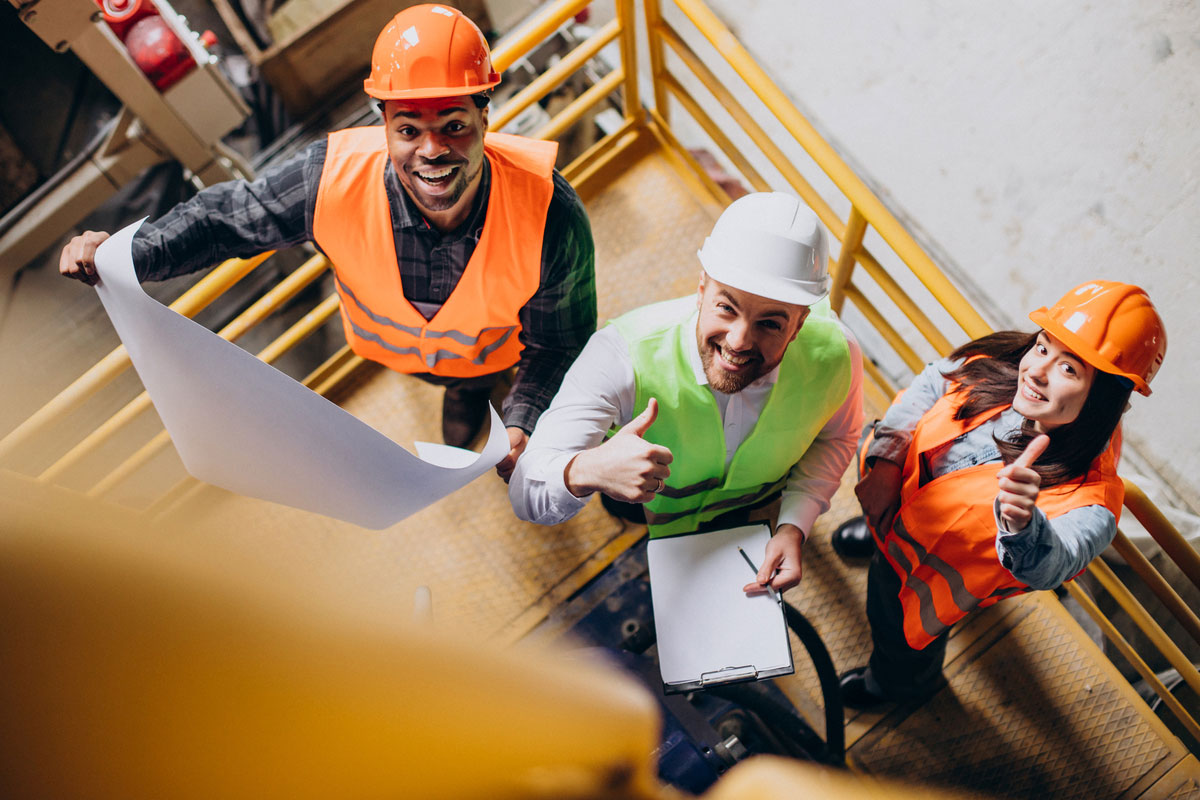 Three-Factory-Workers-Safety-Hats-Discussing-Manufacture-Plan-MEP-in-Construction