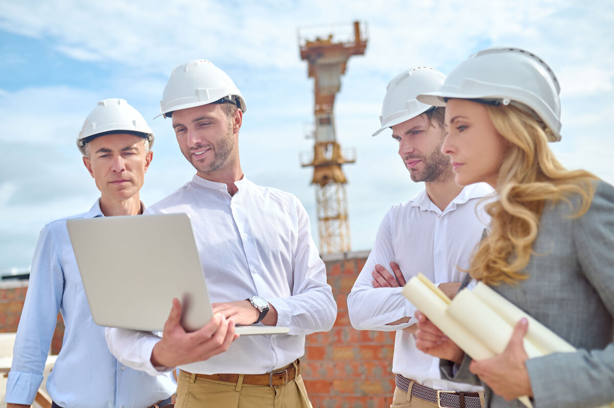 Construction-Engineer-Showing-Something-His-Colleagues-His-Laptop-Tender-in-Construction