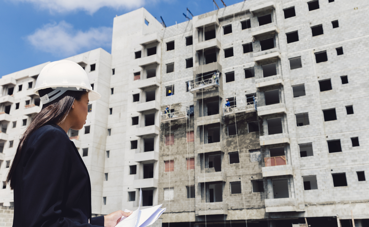 african-american-lady-safety-helmet-with-papers-near-building-construction-Construction-Company-in-United-States